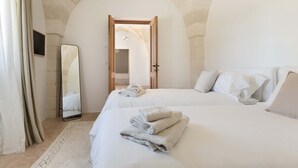 Une chambre à coucher avec un grand lit, un miroir et une porte donnant sur une autre pièce.