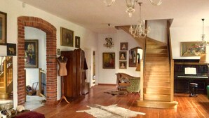 A spacious living room with hardwood floors, a brick archway, a staircase, and a piano. - Holiday Home Baltic Coast Near Beach (Mielno)