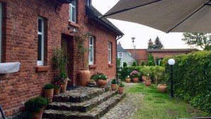 A brick house with a garden, potted plants, and a large umbrella. - Holiday Home Baltic Coast Near Beach (Mielno)