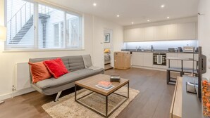 Un apartamento moderno con sala de estar, cocina y una escalera que conduce a un piso superior.