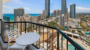 A balcony with a table and chairs overlooking a cityscape with tall buildings and a beach. - Surfers Paradise Beach & Ocean View Unit (Level 13) 
 (Surfers Paradise)