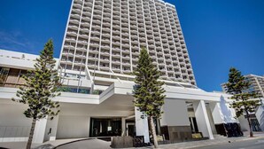 A modern high-rise hotel with a prominent entrance, multiple balconies, and a clear sky. - Surfers Paradise Beach & Ocean View Unit (Level 13) 
 (Surfers Paradise)