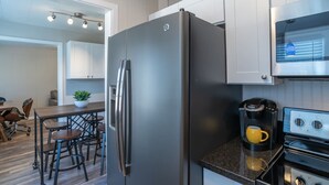 A modern kitchen with a stainless steel refrigerator, a built-in oven, and a coffee maker. - Floyd's Retreat Stylish Home | Walk to Downtown Overland Park (Overland Park)