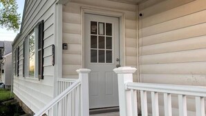 A house with a white front door, a porch with white railings, and a light fixture above the door. - Floyd's Retreat Stylish Home | Walk to Downtown Overland Park (Overland Park)