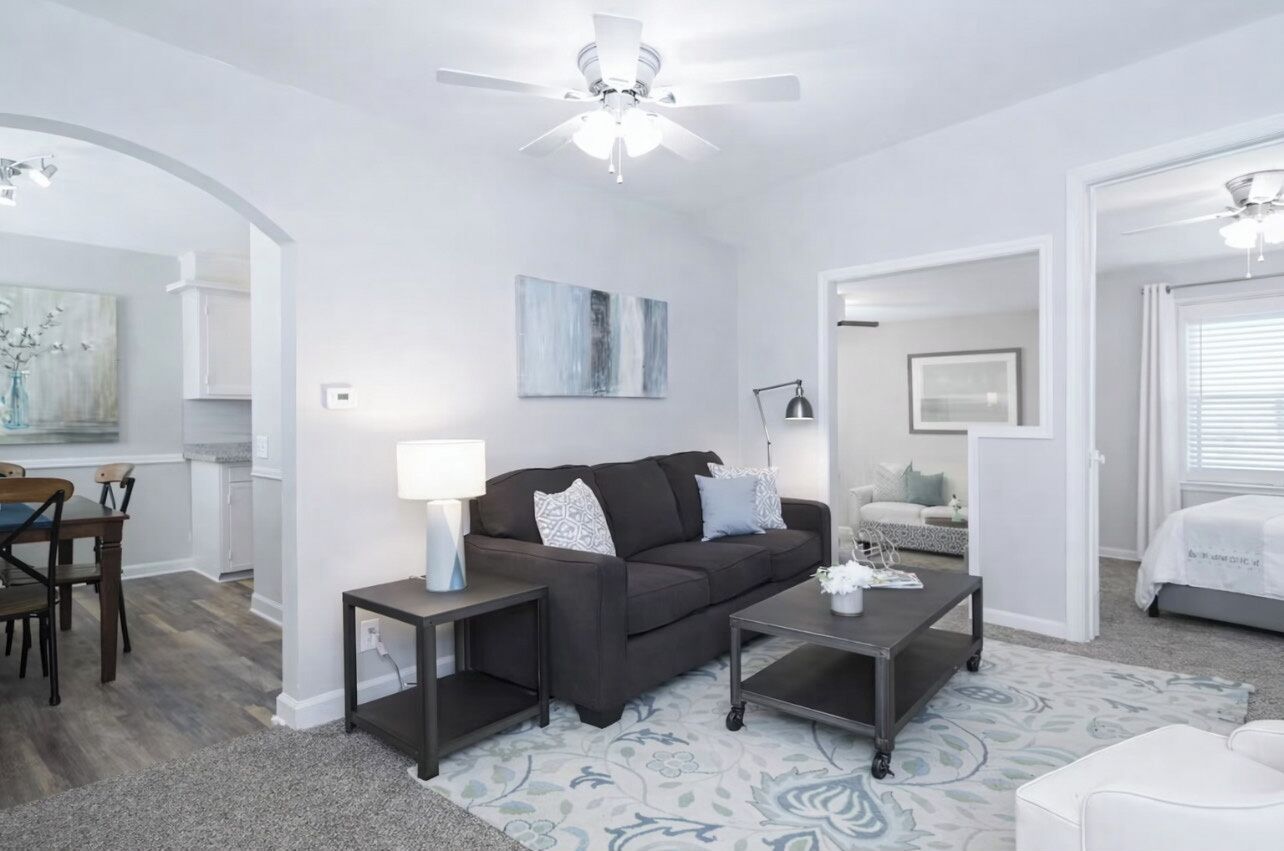 Un salon moderne avec un canapé brun foncé, une table basse et un coin repas comprenant une table et des chaises en bois.