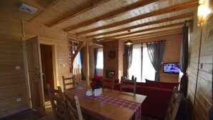 Un interior de madera con una mesa de comedor, sillas, un sofá rojo, una chimenea y un televisor.