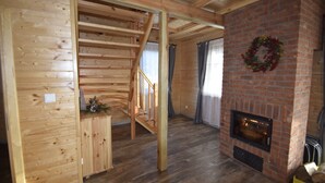 Un interior de madera con chimenea, una escalera y una pared de ladrillo.