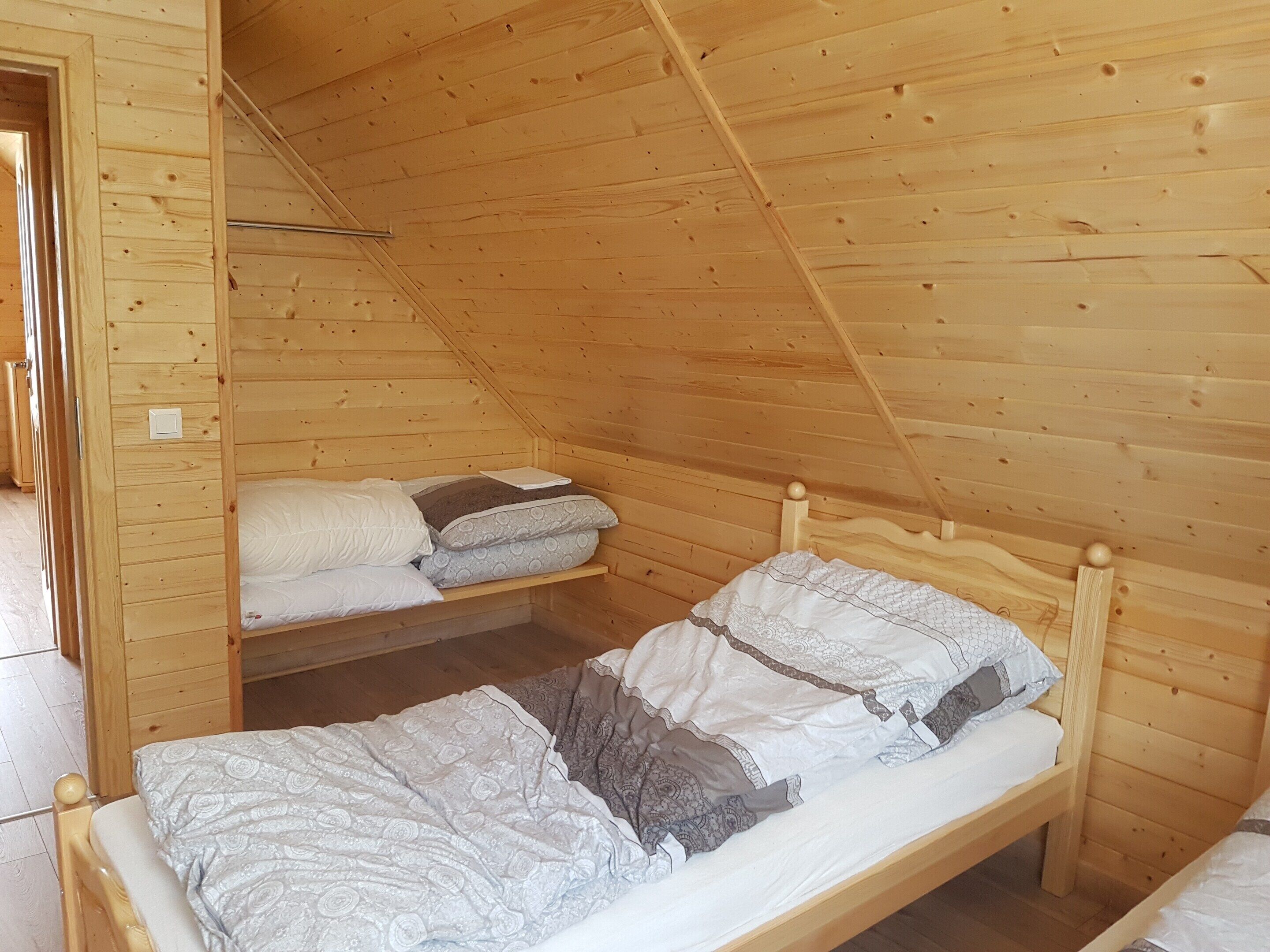 A wooden cabin with a loft-style bedroom featuring a single bed with patterned bedding and a lower bunk bed.