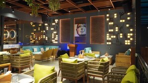Un restaurant doté de mobilier en osier, d’un bar et d’œuvres d’art murales.