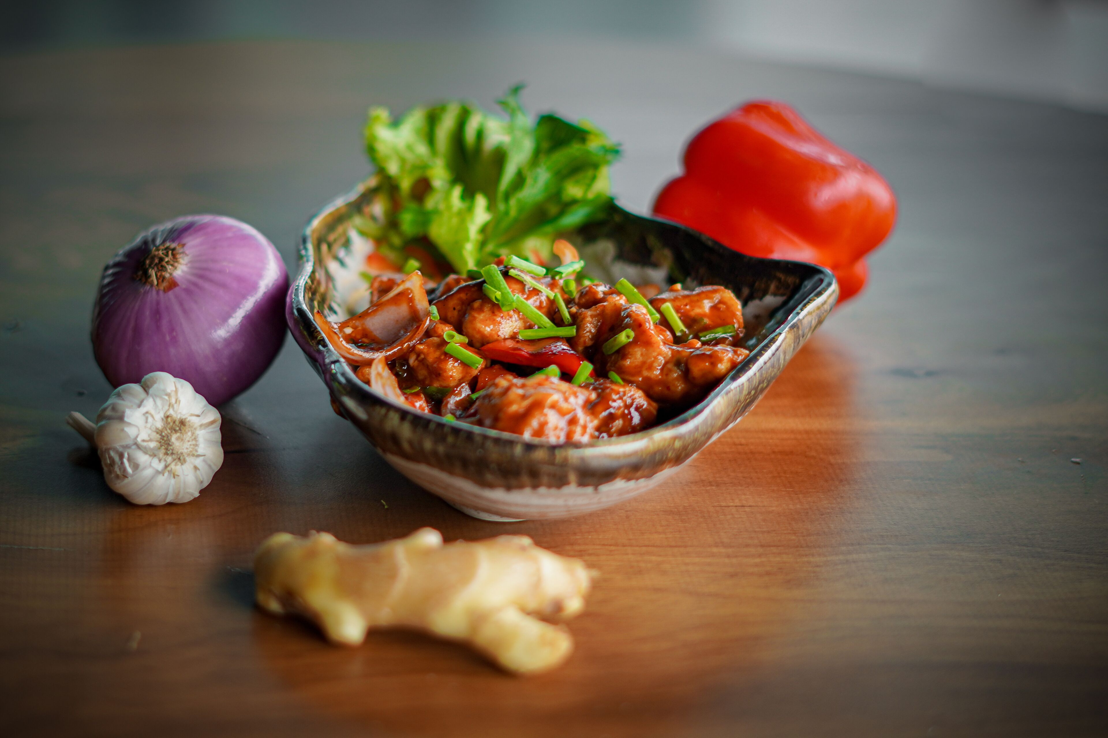 A bowl of food with vegetables and spices on a wooden table.