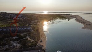 Ett flygbildsbild av ett kustområde med en strand, en rad hus och en vattenyta.
