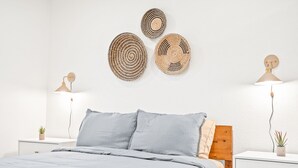 A bedroom with a bed, two bedside tables, a nightstand, a wooden headboard, and wall-mounted lamps. - New Listing! Desert Oasis ~ Hot Tub (Twentynine Palms)