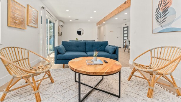 A modern living room with a blue sofa, two wicker chairs, a round coffee table, and artwork on the walls. - New Listing! Desert Oasis ~ Hot Tub (Twentynine Palms)