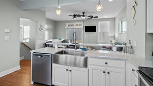 Una cucina moderna con mobili bianchi, elettrodomestici in acciaio inossidabile e lampade a sospensione.