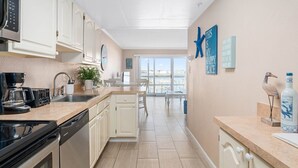 A modern kitchen with white cabinets, a coffee machine, and a view of the city through large windows.