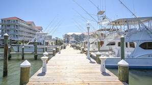 A wooden pier leading to a marina with multiple boats docked.