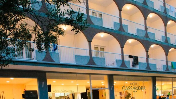 A hotel with a multi-story atrium, outdoor seating, and a visible entrance. - Hotel Cassandra Formerly Hotel Santa Monica (Llucmajor)