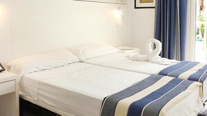 A hotel room with two beds, a painting of a beach, a framed picture, and a window with curtains. - Hotel Cassandra Formerly Hotel Santa Monica (Llucmajor)