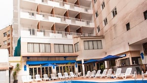 A hotel with a swimming pool, outdoor seating, and a multi-story building with balconies. - Hotel Cassandra Formerly Hotel Santa Monica (Llucmajor)