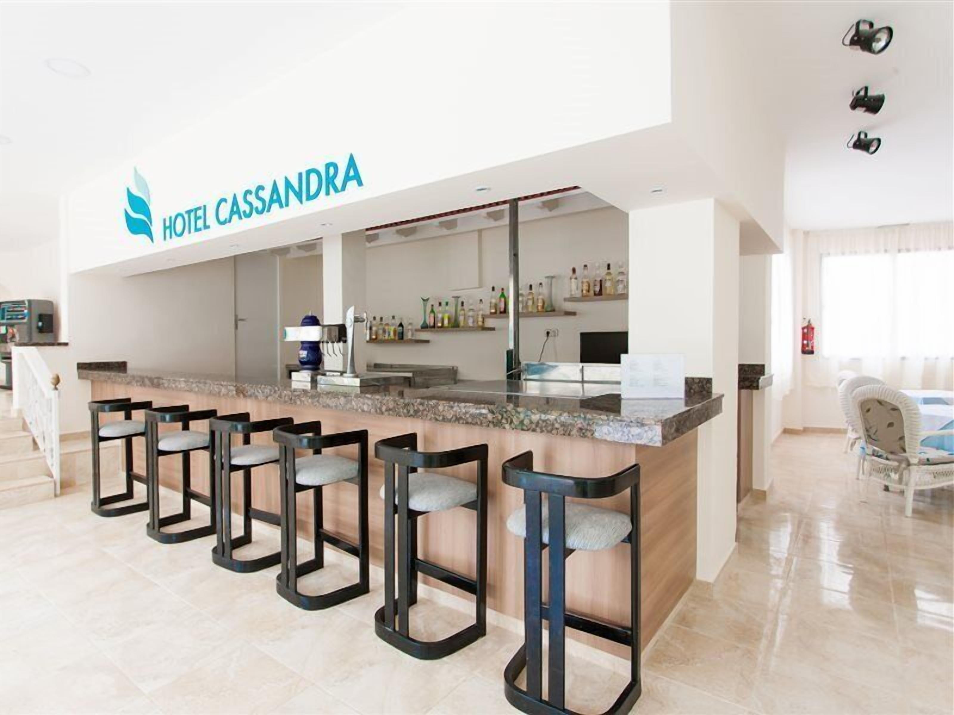 Un vestíbulo de hotel con mostrador de recepción, zona de bar y asientos.