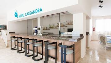 Un vestíbulo de hotel con mostrador de recepción, zona de bar y asientos.