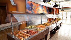 A buffet with various food items and drinks, a wooden counter, and a colorful mural on the wall. - Hotel Cassandra Formerly Hotel Santa Monica (Llucmajor)