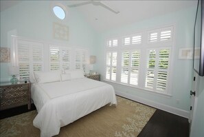 A bedroom with a large bed, white shutters on the windows, and a small round skylight. - 3.5 blocks to the beautiful Rehoboth Beach (Rehoboth Beach)