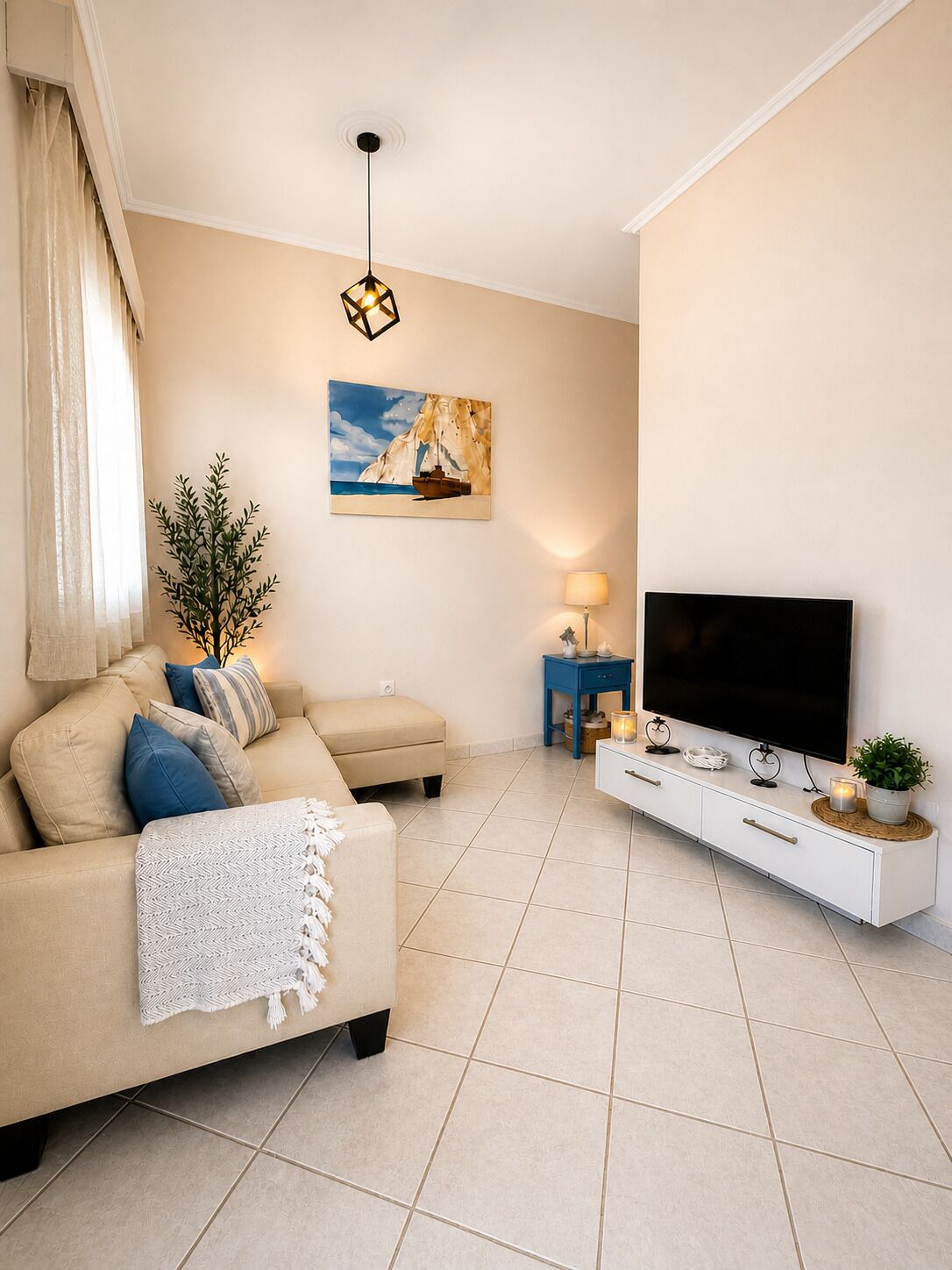 A living room with a sofa, TV, and a painting on the wall.
