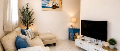 A living room with a sofa, TV, and a painting on the wall.