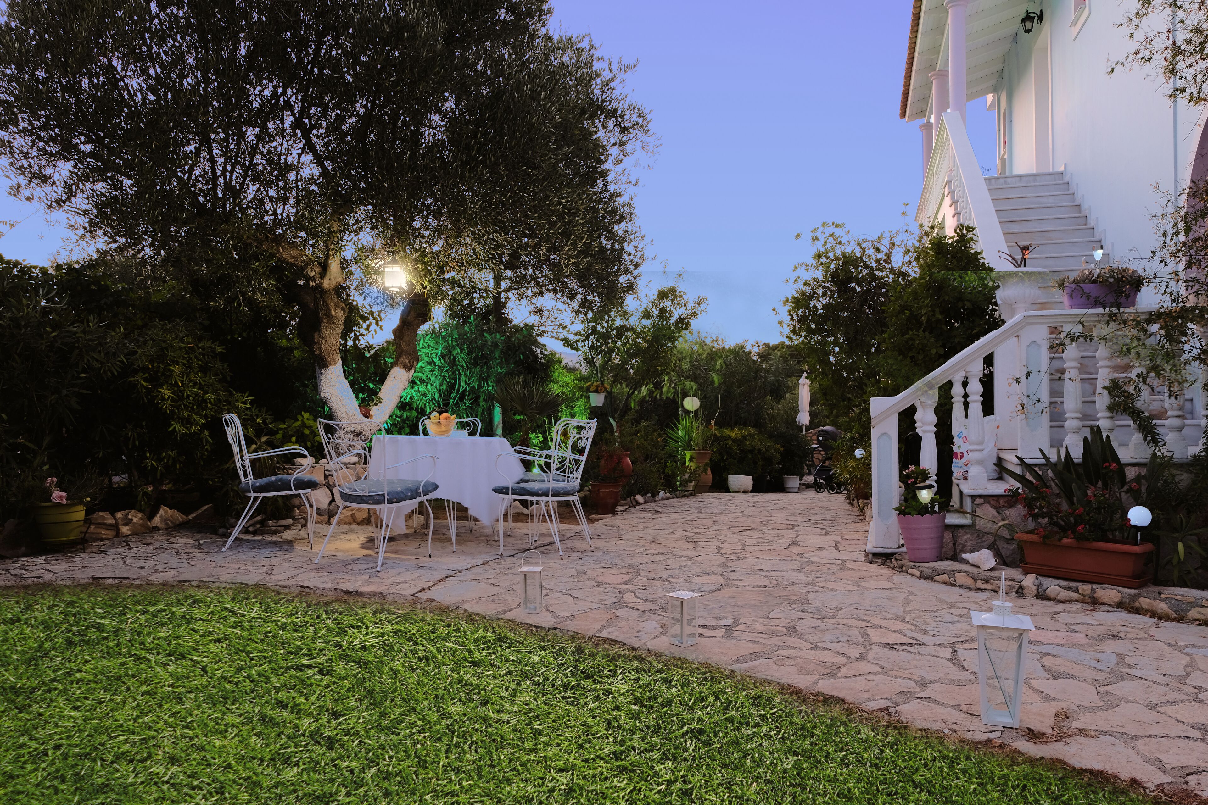 A stone patio with outdoor seating, a staircase, and potted plants.