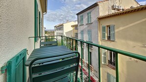 A narrow street with buildings on either side, a metal staircase, and a green railing.