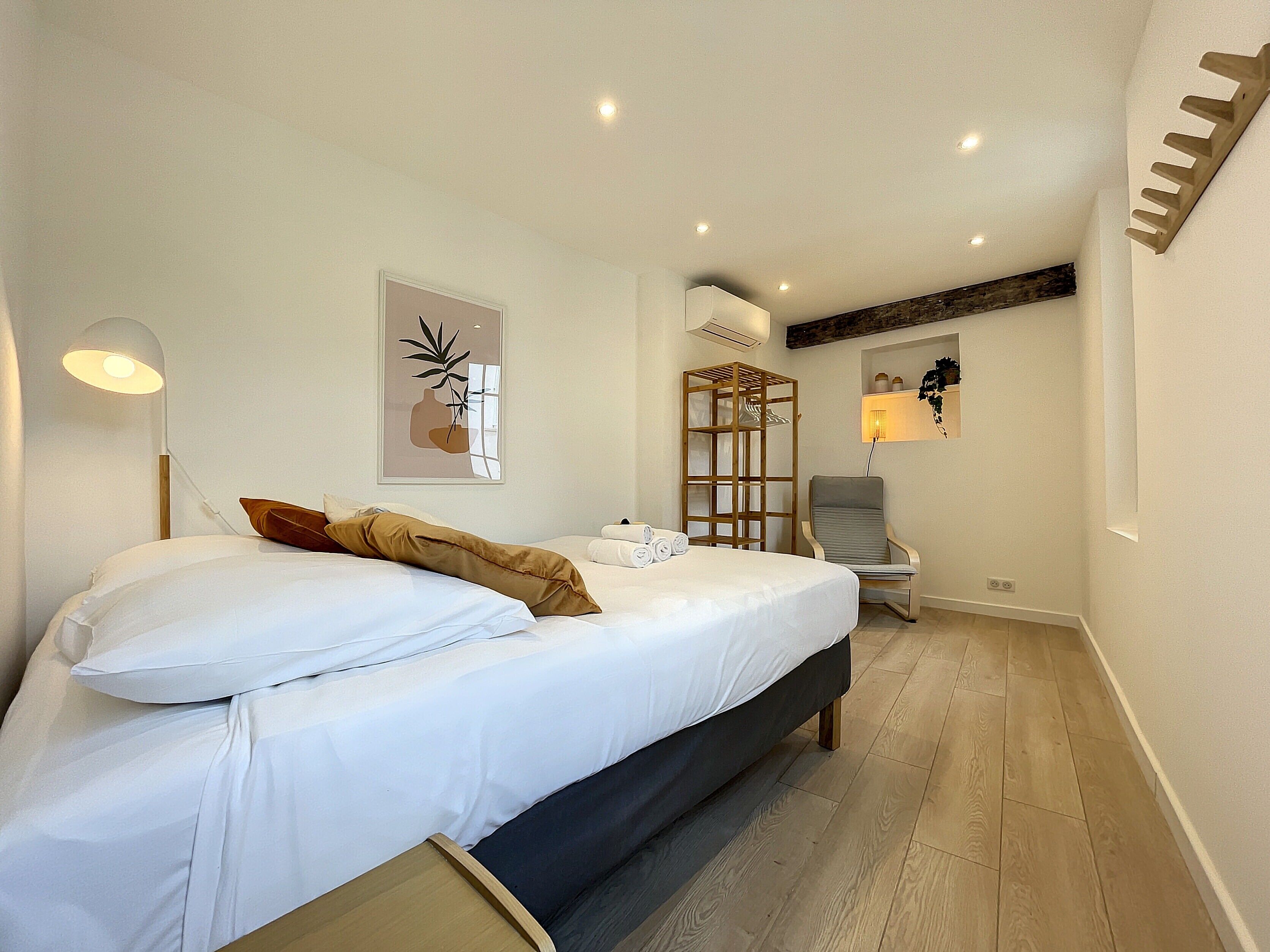 Ein ordentlich eingerichtetes Schlafzimmer mit einem Bett, einer Nachttischlampe und einem an der Wand befestigten Regal mit Dekoration.