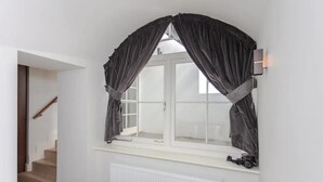 A bedroom with a large window, a radiator below, and a staircase leading to another room. - Spacious and Modern Apartment in Pimlico (London)