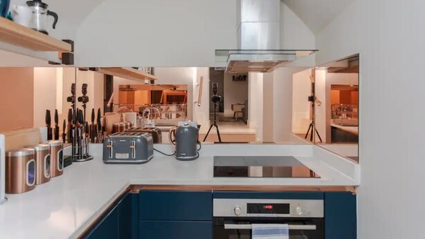 A modern kitchen with a central island, stainless steel appliances, and a large range hood. - Spacious and Modern Apartment in Pimlico (London)