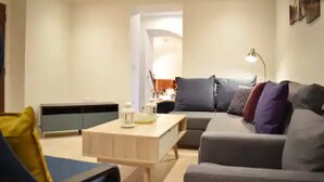 A modern living room with a grey sofa, a wooden coffee table, and a blue armchair. - Spacious and Modern Apartment in Pimlico (London)