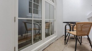 A room with a large sliding glass door, a small table with chairs, and a wicker chair. - Spacious and Modern Apartment in Pimlico (London)