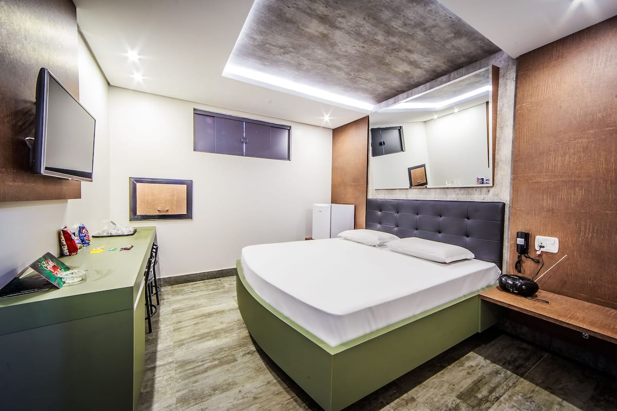 A modern hotel room with a bed, desk, and a flat-screen TV mounted on the wall.