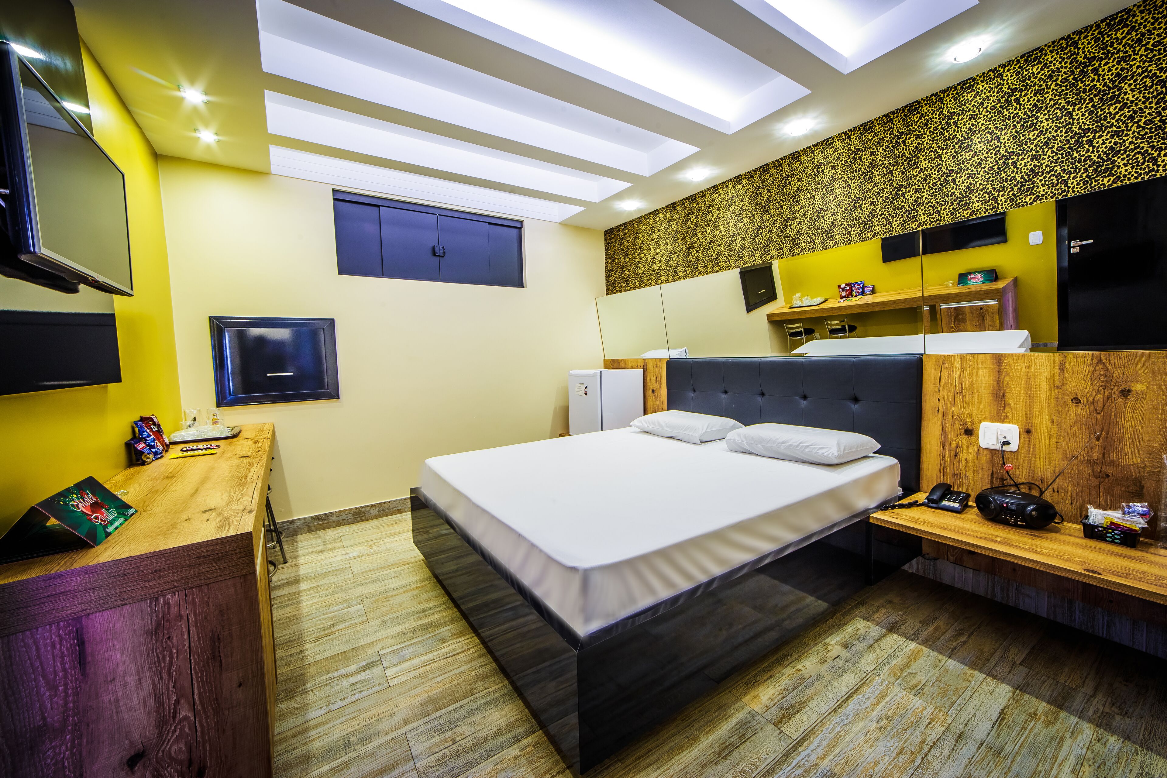 A modern bedroom with a bed, bedside table, and a desk with a chair.