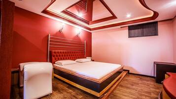 Un dormitorio moderno con una pared de acento roja, un cabecero capitonado, piso de madera y un armario empotrado.