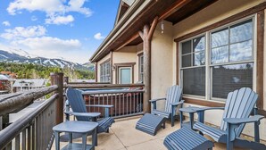 Ein Balkon mit Adirondack-Stühlen und einem Tisch, mit Blick auf ein Gebirge.