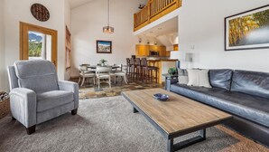 Ein geräumiges Wohnzimmer mit grauem Sofa, einem Holztisch und einem Essbereich mit Holztisch und Stühlen.