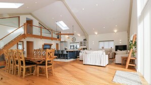 A spacious loft with a wooden dining area, a kitchen, a living room, and a staircase leading to an upper level. - Bilsham Meadows (Bristol)