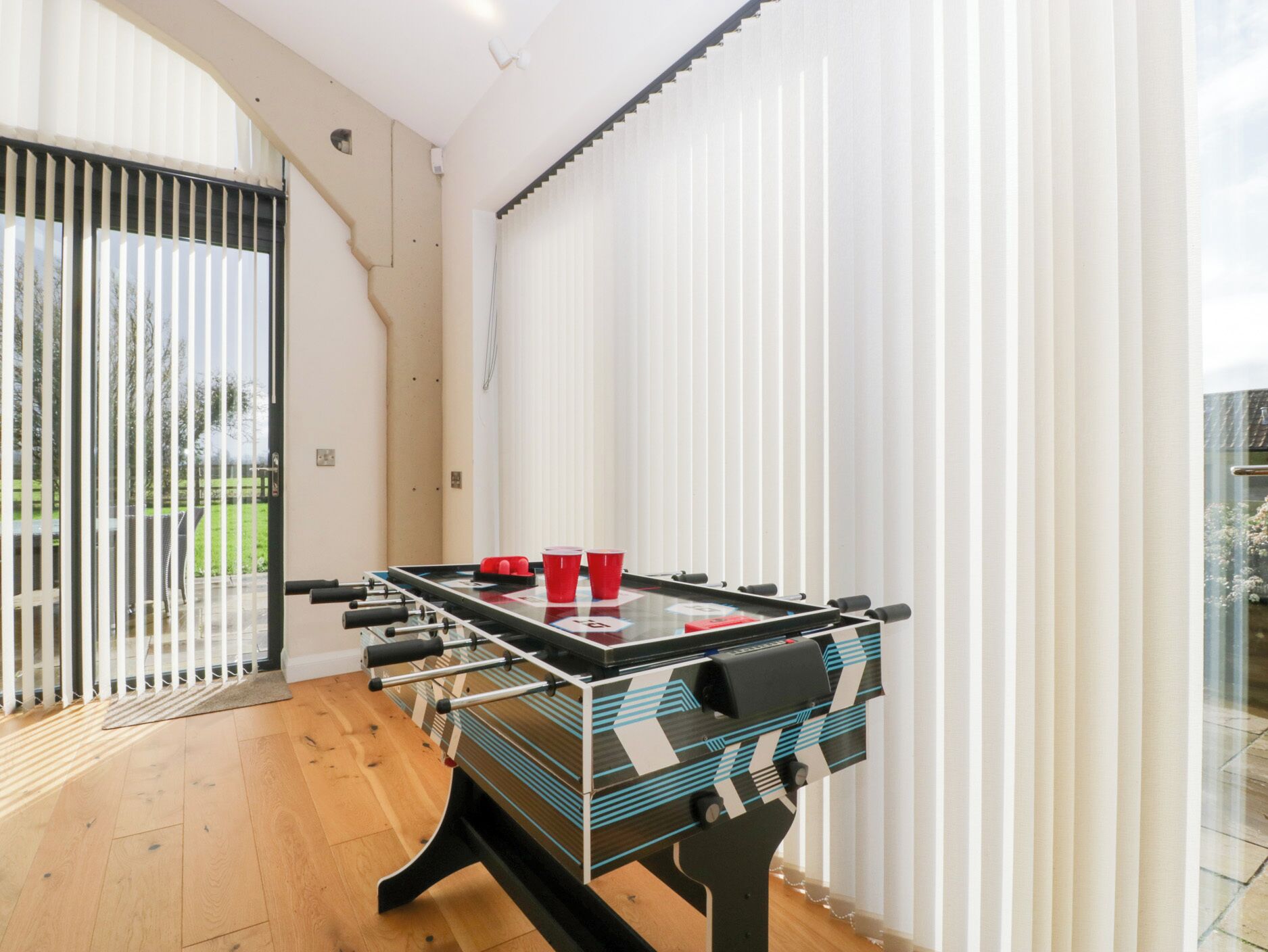 Uma mesa de futebol de mesa em um quarto com uma janela grande e vista para o verde lá fora.