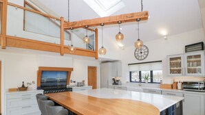 A modern kitchen with a large island, a dining area, and a loft space. - Bilsham Meadows (Bristol)
