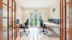Un ufficio moderno con due scrivanie, due sedie e due monitor computer.