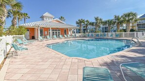 A pool area with lounge chairs and a building with a distinctive roof.