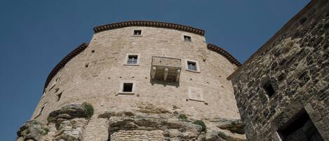 A stone tower with multiple windows and a door, part of a larger building.