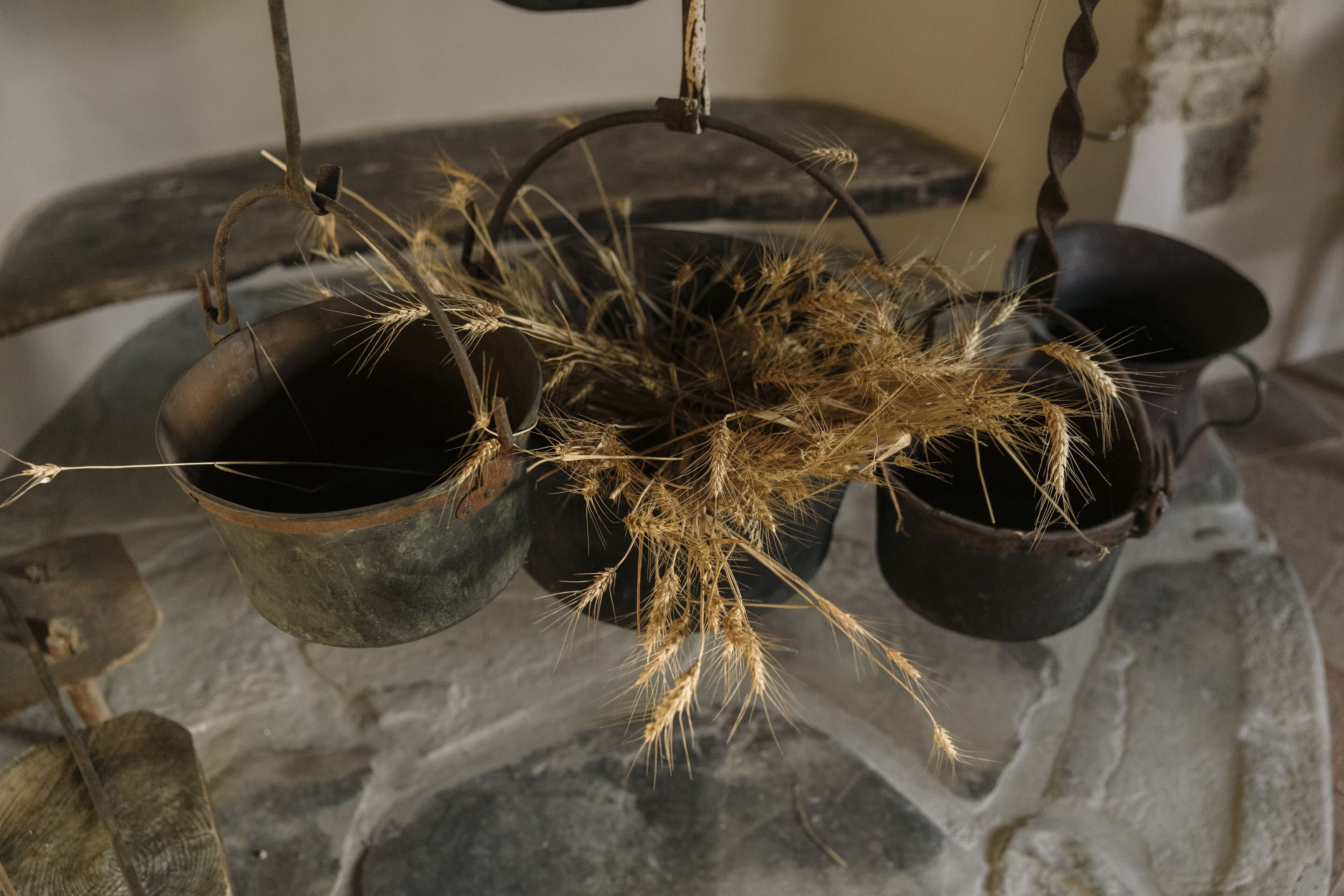 Een rustieke omgeving met hangende potten en gedroogde planten, wat een historische of traditionele sfeer oproept.