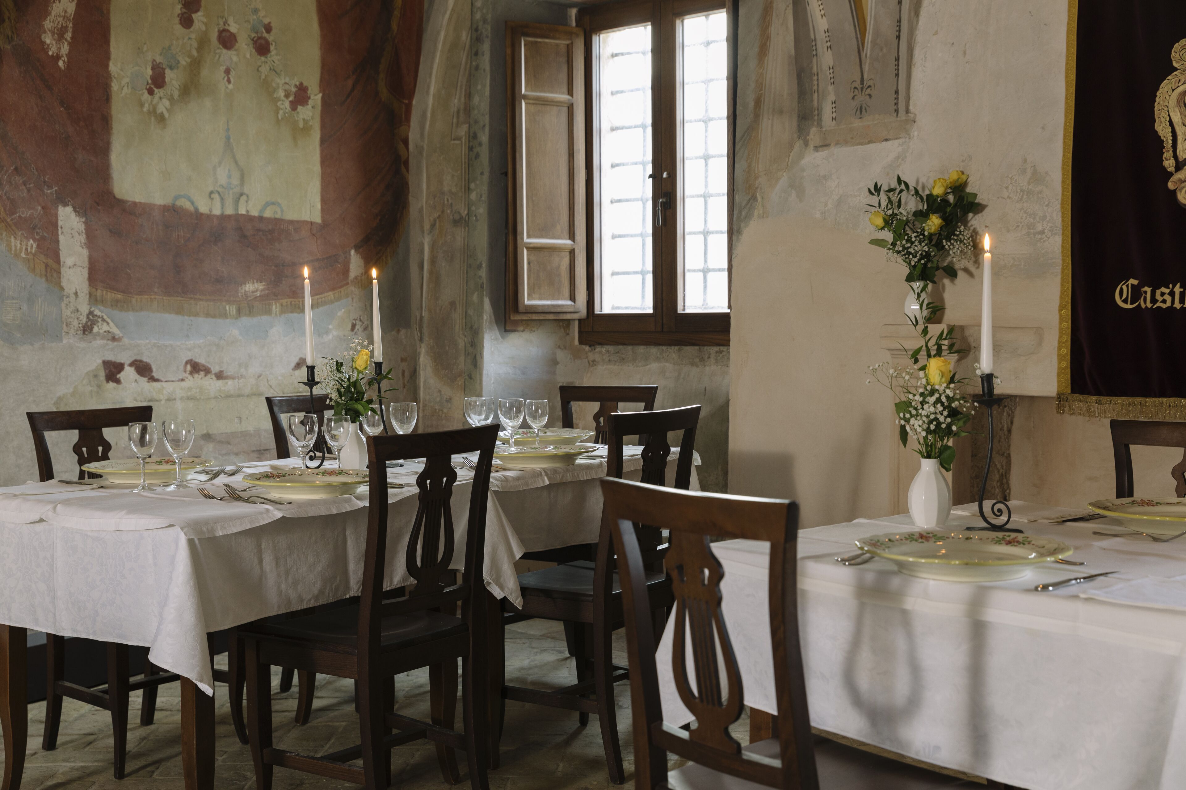 A dining area with a table set for four, candles, and a vase with flowers.