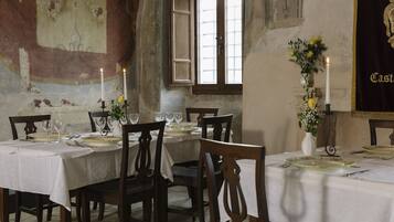 A dining area with a table set for four, candles, and a vase with flowers.